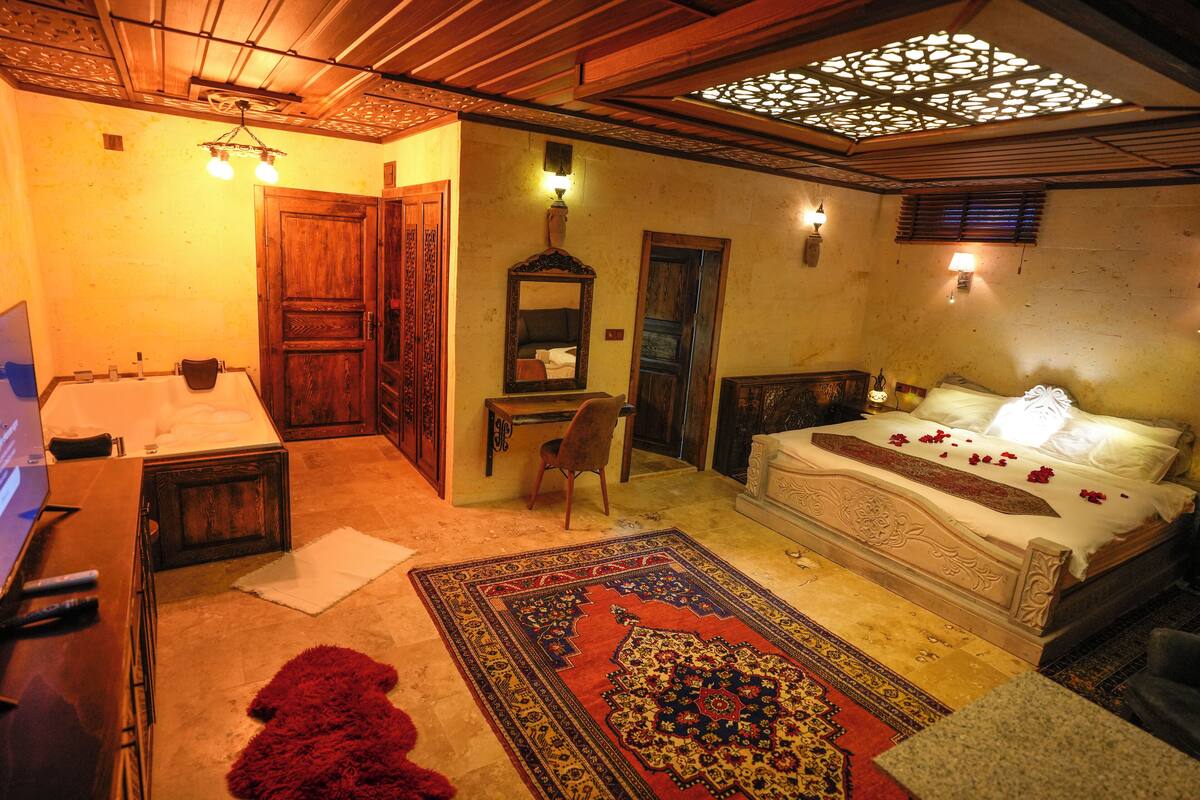 A traditional room with a bed, a desk, a chair, and a television.