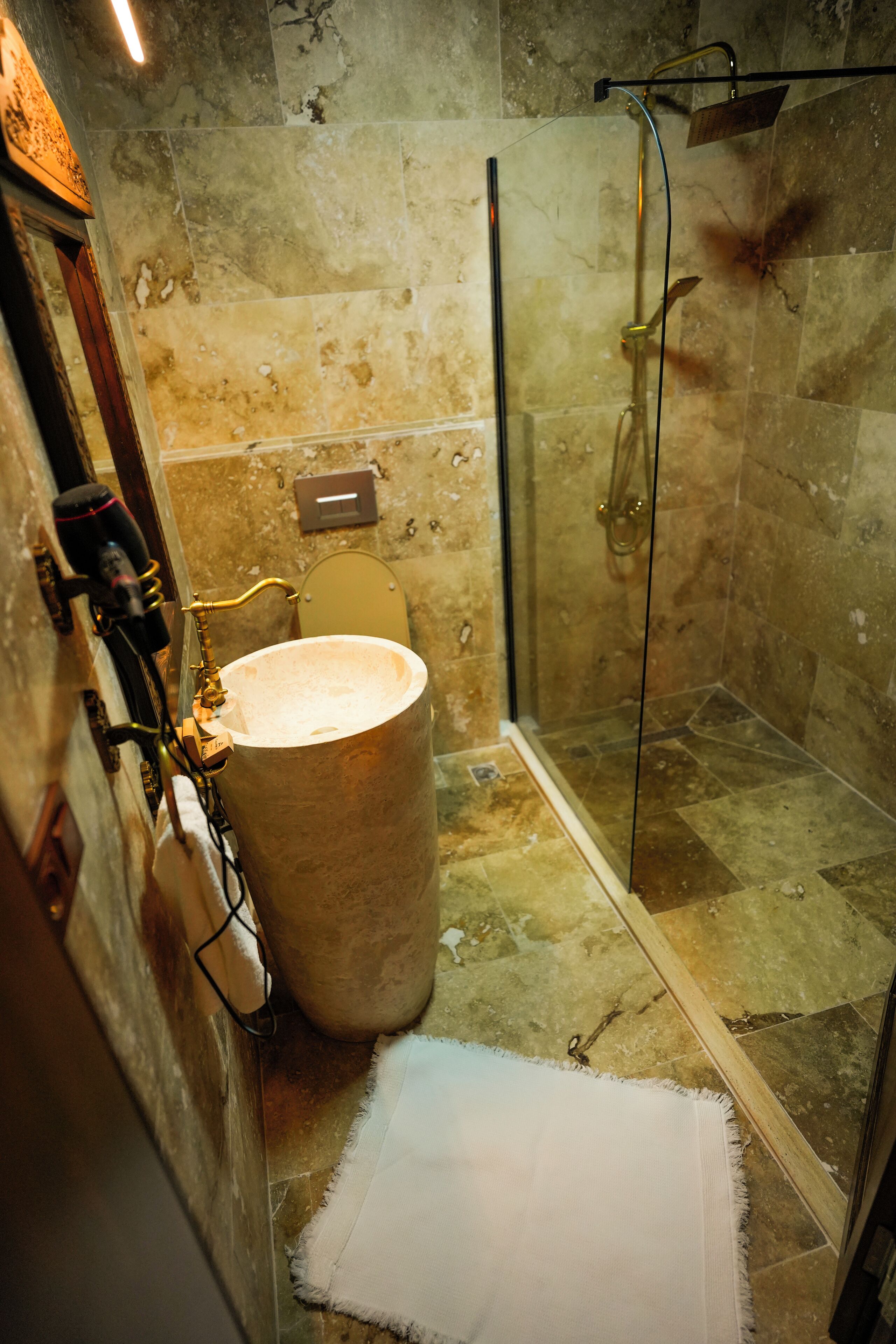 A bathroom with a large sink, a glass shower enclosure, and a mirror.