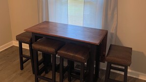 Un comedor con una mesa de madera y cuatro taburetes a juego.