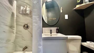 A bathroom with a bathtub, a sink, a toilet, and a mirror.
