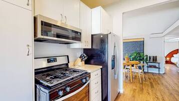 A modern kitchen with a built-in oven, a black refrigerator, and wooden flooring.