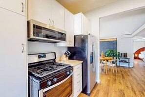 A modern kitchen with a built-in oven, a black refrigerator, and wooden flooring. - Mid-Century Treehouse with Yard and Views! AMAZING Location! Pet-friendly! (Spring Valley)