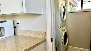 A laundry area with a washing machine and dryer, a countertop, and a window with a view of the outside.