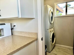 A laundry area with a washing machine and dryer, a countertop, and a window with a view of the outside. - Mid-Century Treehouse with Yard and Views! AMAZING Location! Pet-friendly! (Spring Valley)