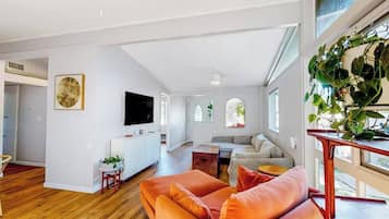 A spacious living area with a sofa, a television, and a plant.