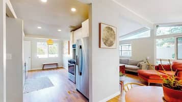 A modern kitchen with a refrigerator, oven, and dining area with a table and chairs.