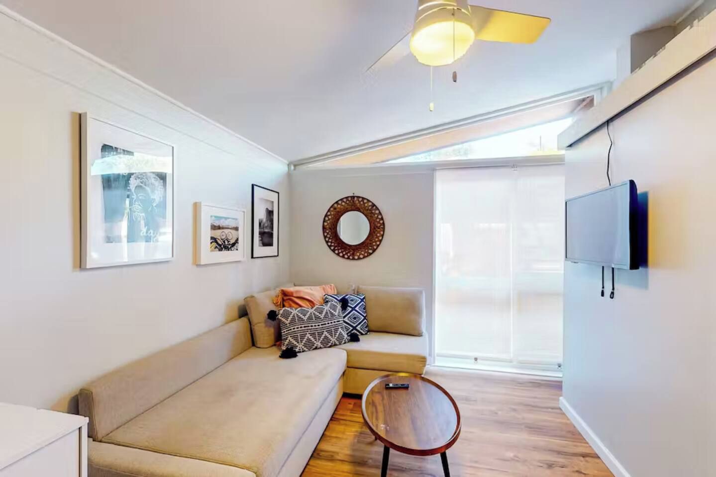 Uma sala de estar moderna com um sofá, uma mesa redonda pequena e um ventilador de teto.