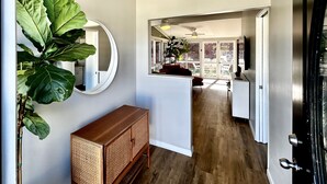 Une cuisine moderne avec une grande plante, un meuble en bois et un coin repas comprenant un canapé rouge et un ventilateur de plafond.