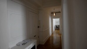 A narrow hallway with a wooden floor, white walls, and a door at the end. - Beautiful 2-bed Flat in London (London)