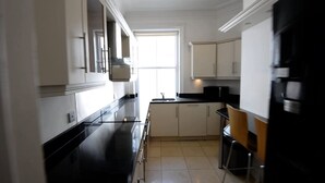 A modern kitchen with white cabinets, a black countertop, and a window providing natural light. - Beautiful 2-bed Flat in London (London)