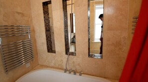A bathroom with a bathtub, a shower, and a towel rack. - Beautiful 2-bed Flat in London (London)