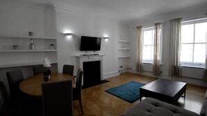 A living room with a fireplace, a television, a dining table with chairs, and a sofa. - Beautiful 2-bed Flat in London (London)