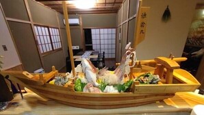 A traditional Japanese boat with a wooden interior, a table, and chairs in the background.