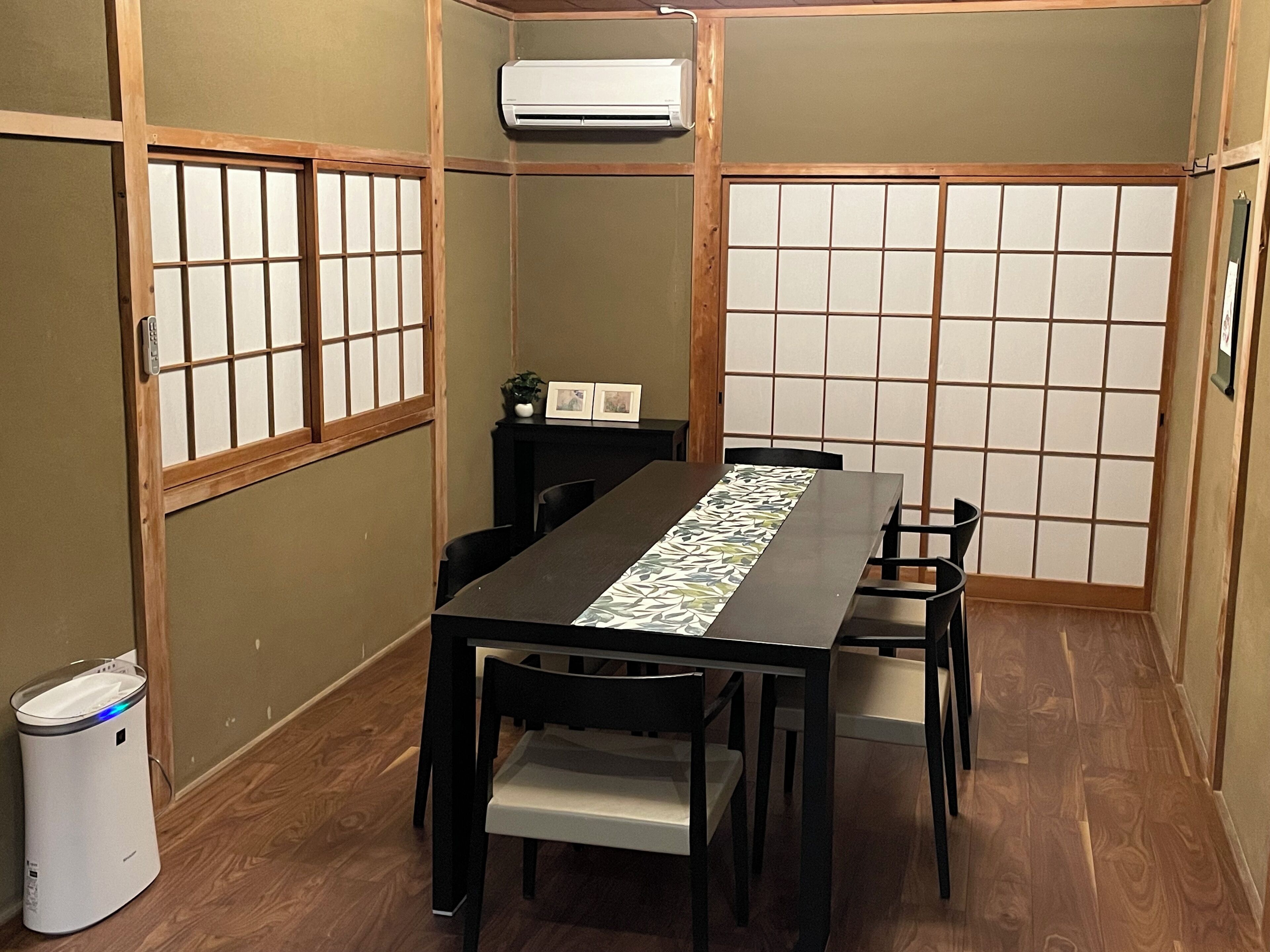 A traditional Japanese-style room with tatami flooring, a low table with a patterned table runner, and shoji screens.