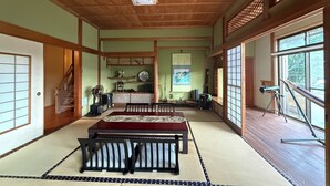 A traditional Japanese room with tatami flooring, a low wooden ceiling, and sliding doors.