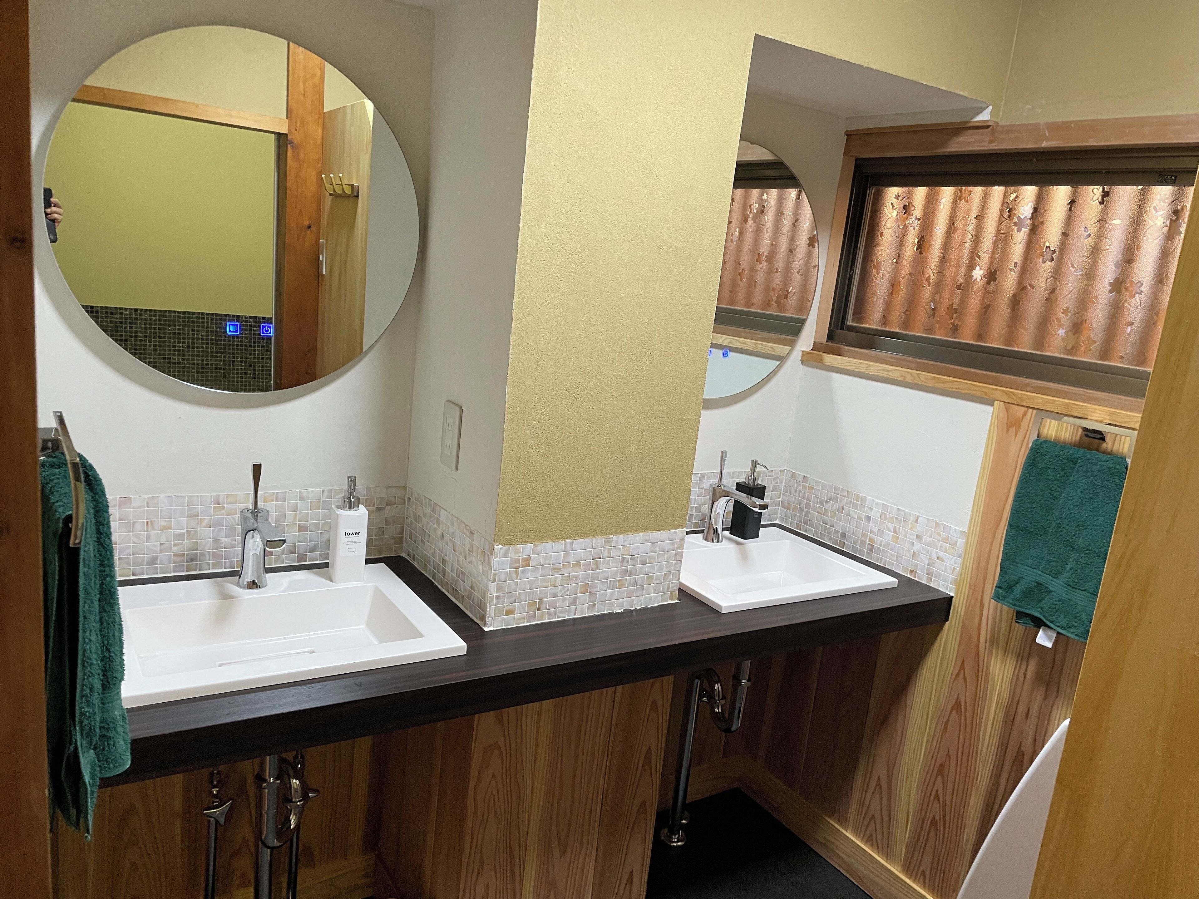 A bathroom with two sinks, a mirror, and a window with curtains.