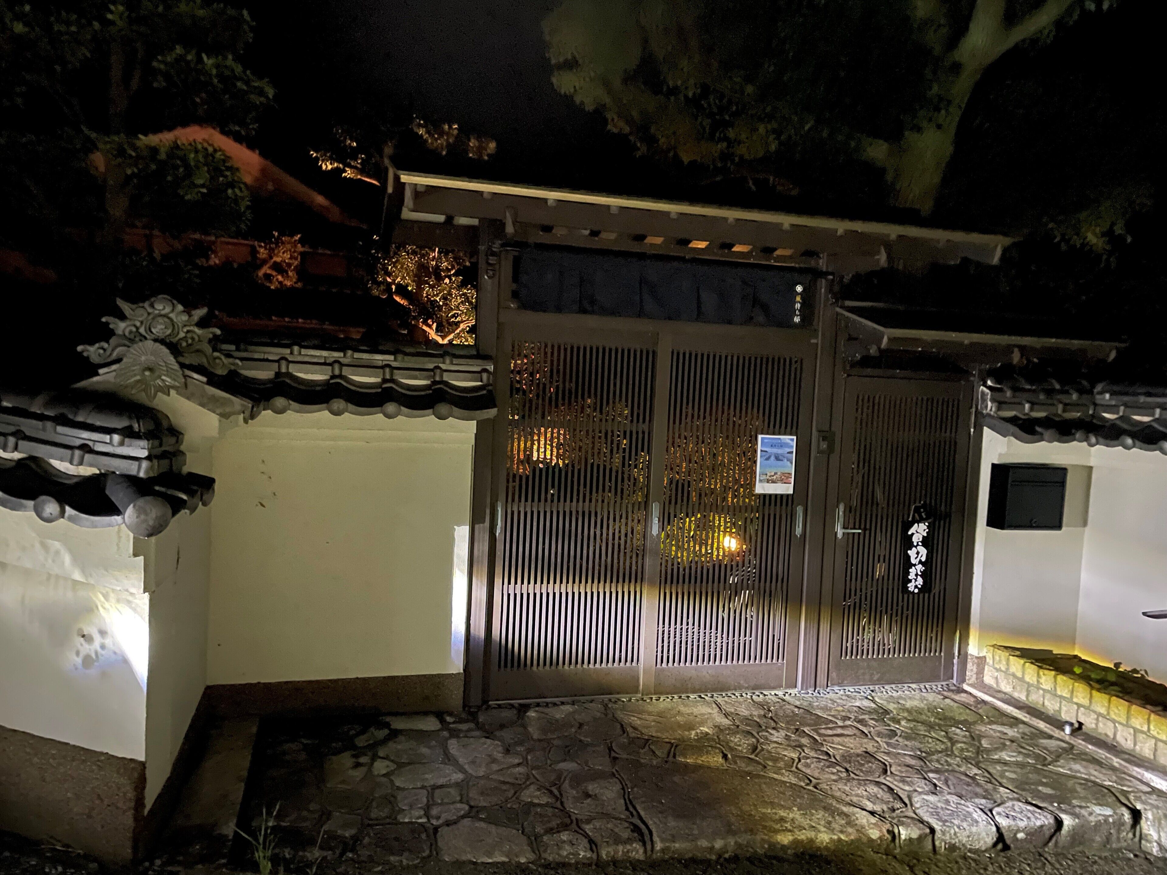 A traditional gate with a sign, stone steps, and a tiled roof.