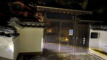 A traditional gate with a sign, stone steps, and a tiled roof.