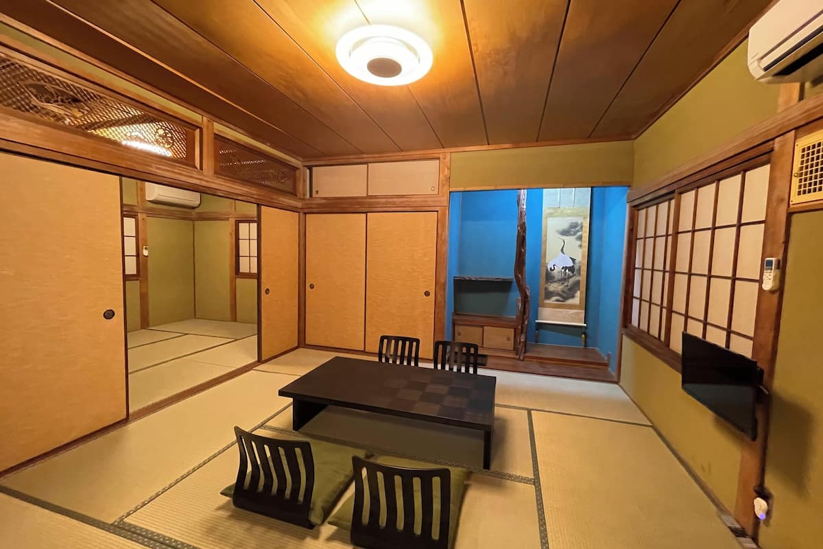 Ett traditionellt japanskt rum med tatamimattor på golvet, ett lågt bord med kuddar och skjutdörrar.
