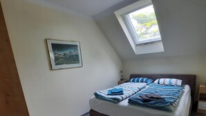 A bedroom with a bed, a skylight, a painting, and a nightstand. - Comfortable vacation apartment Senzig, 150 m to the beach (Königs Wusterhausen)