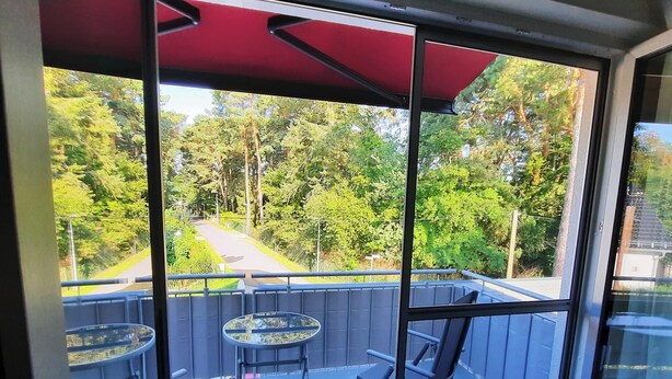 A balcony with a glass door, a table, and a chair. - Comfortable vacation apartment Senzig, 150 m to the beach (Königs Wusterhausen)