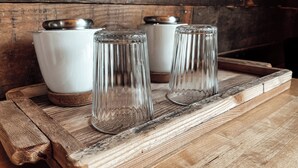 Trois récipients en verre, dotés de couvercles en métal, sont posés sur un plateau en bois.