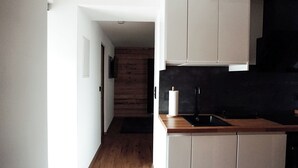 Une cuisine moderne avec un plancher en bois, un pare-feu noir et des armoires de couleur claire.