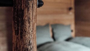 Une tête de lit en bois au fini rustique, une barre métallique et un lit doté d’un matelas et de coussins de couleur claire.