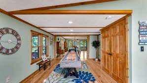 A spacious room with a foosball table, wooden flooring, a large wall clock, and a wooden door with a sign. - Peaceful Lakefront Cabin Retreat with Hot Tub! (Deerfield)