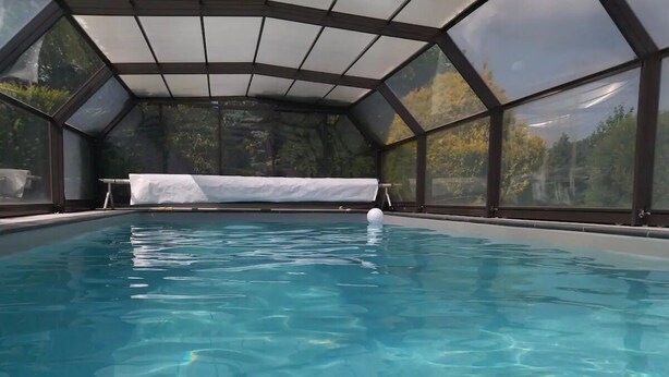 An indoor swimming pool with clear water, surrounded by a glass enclosure with a metal frame. - La Chèvrerie (Taintrux)