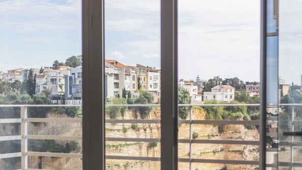 Uma varanda com vista para uma área residencial e uma paisagem rochosa.