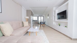 Uma sala de estar moderna com um sofá, uma mesa de centro e uma TV fixada na parede.