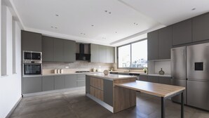Uma cozinha moderna com armários cinza, eletrodomésticos de aço inoxidável e uma ilha grande.