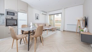 Uma cozinha moderna com eletrodomésticos embutidos, um espaço de refeições com mesa e cadeiras, e uma janela grande que proporciona iluminação natural.