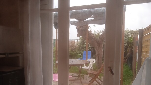 A room with a large window, a table, and two chairs outside. - T3 Avec Jardin (Agde)