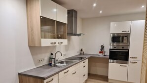 Une cuisine moderne avec des armoires blanches, des appareils en acier inoxydable et un plan de travail en bois.