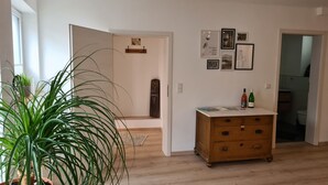 Une pièce avec une commode en bois, une plante en pot et un mur orné de tableaux.