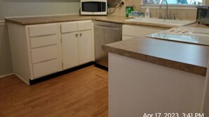 A kitchen with white cabinets, a microwave, a sink, and a countertop.