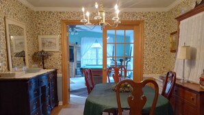 A dining room with a wooden table, chairs, a chandelier, and a view of the backyard through a glass door.