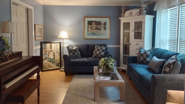 A living room with a piano, sofas, a coffee table, and a cabinet.
