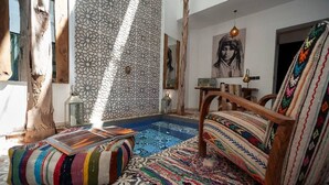 A cozy room with a patterned rug, a wooden chair, and a bookshelf. - Riad Familial Privatisé au Calme Avec vue sur Marrakech (Marrakech)