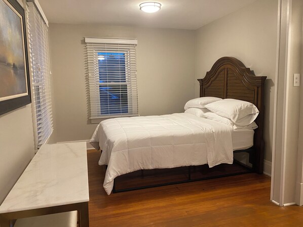 A bedroom with a bed, a wooden headboard, a window with blinds, a bedside table, and a framed picture on the wall. - Williamsville Village Farm House Convenient location for visting Niagara Falls (Buffalo)