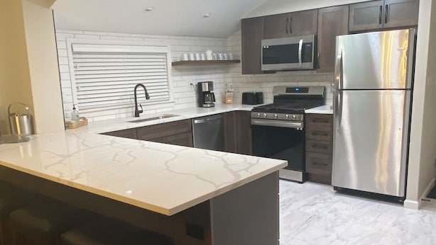 Una cocina moderna con una isla central, electrodomésticos de acero inoxidable y suelo de madera.