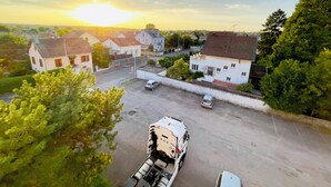 Un espace de stationnement où sont garés un camion et une voiture, entouré de bâtiments résidentiels et de verdure.