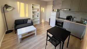 Un espace de vie compact comprenant un coin cuisine, un canapé, une table basse et une table à manger.