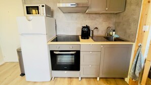 Une cuisine compacte équipée d’un réfrigérateur, d’un four, d’un four à micro-ondes et d’une machine à café.