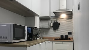 A compact kitchen with white cabinets, a microwave, a coffee maker, and a stove. - Ribera villa relax 2 (Ribera)