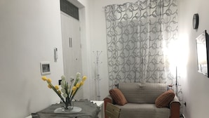 A living room with a white table, a sofa with cushions, a chair, and a curtain with a circular pattern. - Ribera villa relax 2 (Ribera)