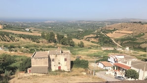 A rural landscape with a mix of agricultural fields, scattered houses, and a distant view of the sea. - Ribera villa relax 2 (Ribera)