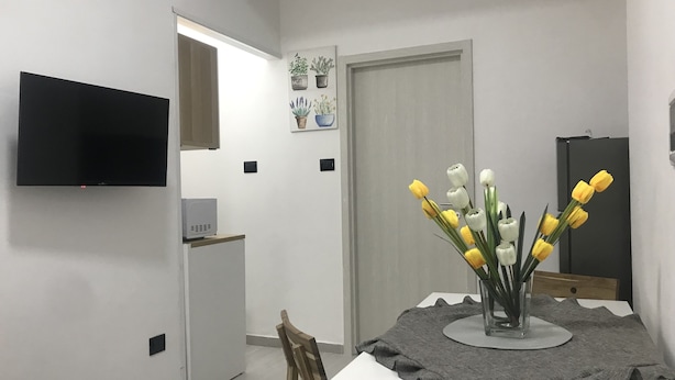 A modern dining area with a white table, a grey table runner, and a vase with yellow and white tulips. - Ribera villa relax 2 (Ribera)